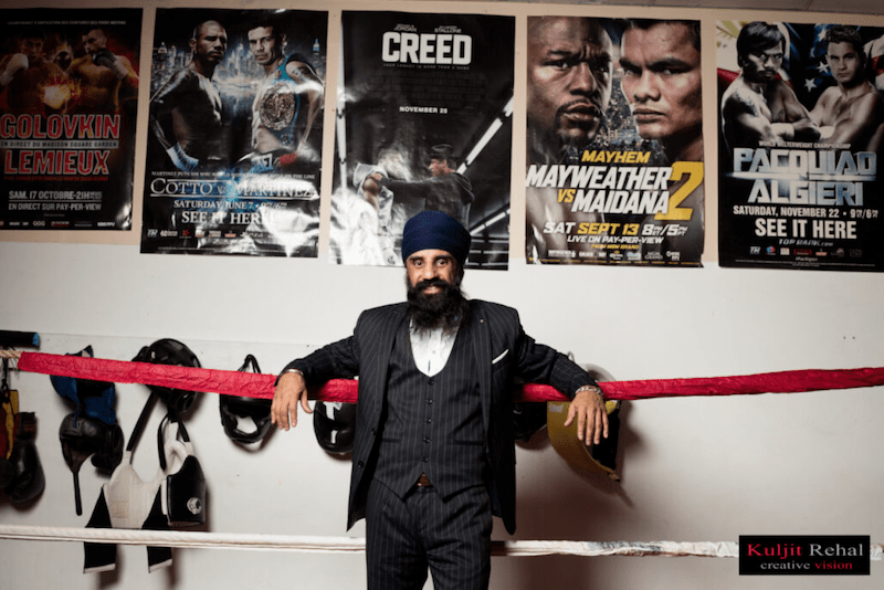 Pardeep Singh Nagra, standing in his suit in front of boxing posters